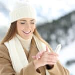 woman hydrating hands skin with moisturizer cream in a snowy mountain