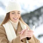 woman hydrating hands skin with moisturizer cream in a snowy mountain