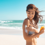 Beautiful young latin woman applying suntan lotion at sea with copy space.