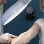 Dermatologist examining the arms of female patient in clinic