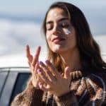 woman applying a sunscreen on her face in snowy mountains in winter